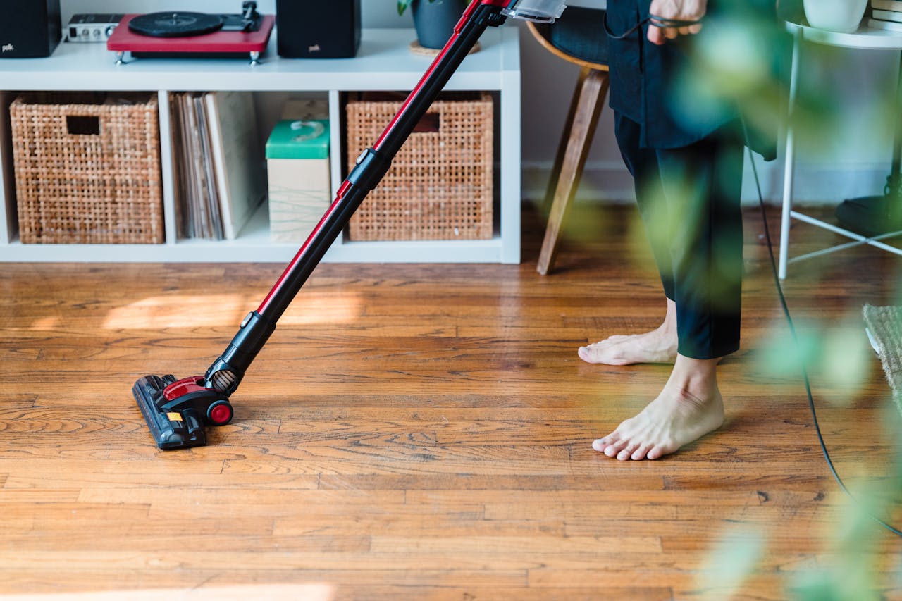 home-services-004 A person vacuuming wooden flooring in a cozy room, emphasizing clean living space.